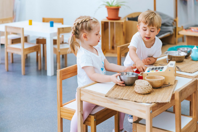 Niños jugando en una mesa en un entorno de educación infantil siguiendo la LOMLOE